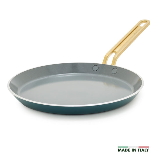 Teal crepe pan with a gold handle on a white background