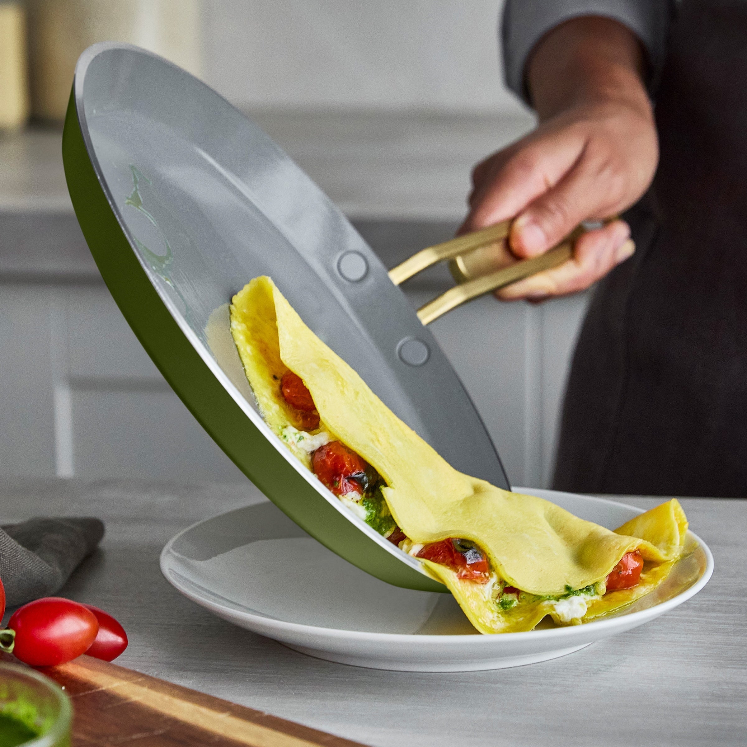 Crepe sliding off of a pan onto a white plate.