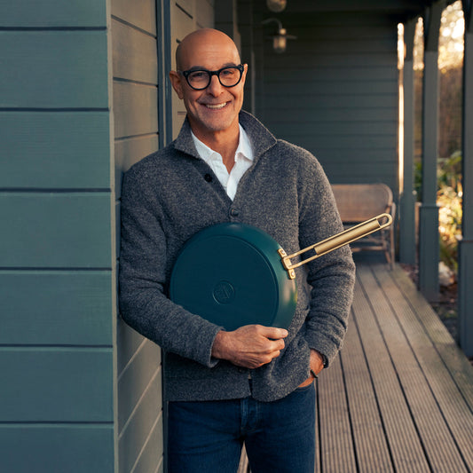 Stanley Tucci holding a teal frypan on a porch
